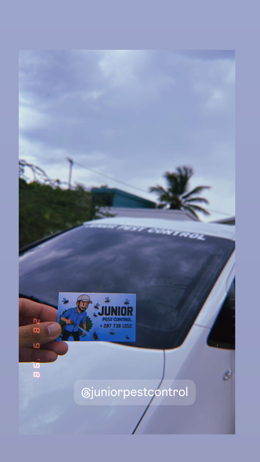 Junior Pest Control business card in front of the company vehicle in Aruba